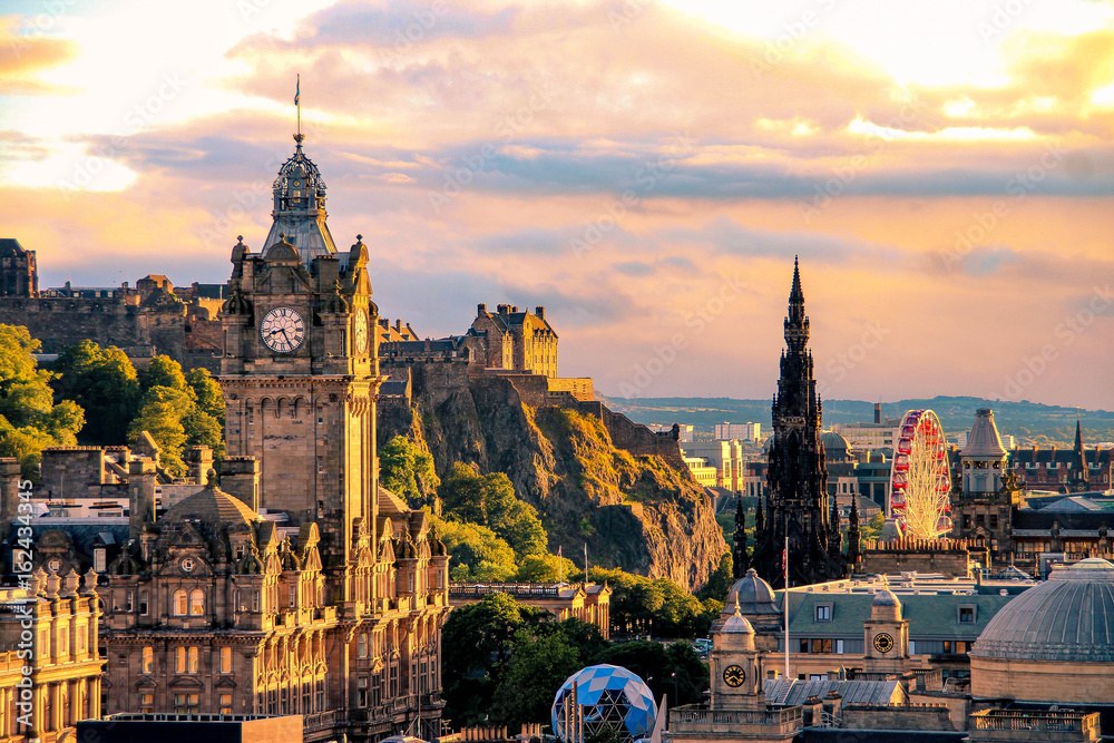 Edinburgh skyline at sunset with the Balmoral clock tower, Edinburgh Castle on its rock, the Scott Monument and a Ferris wheel